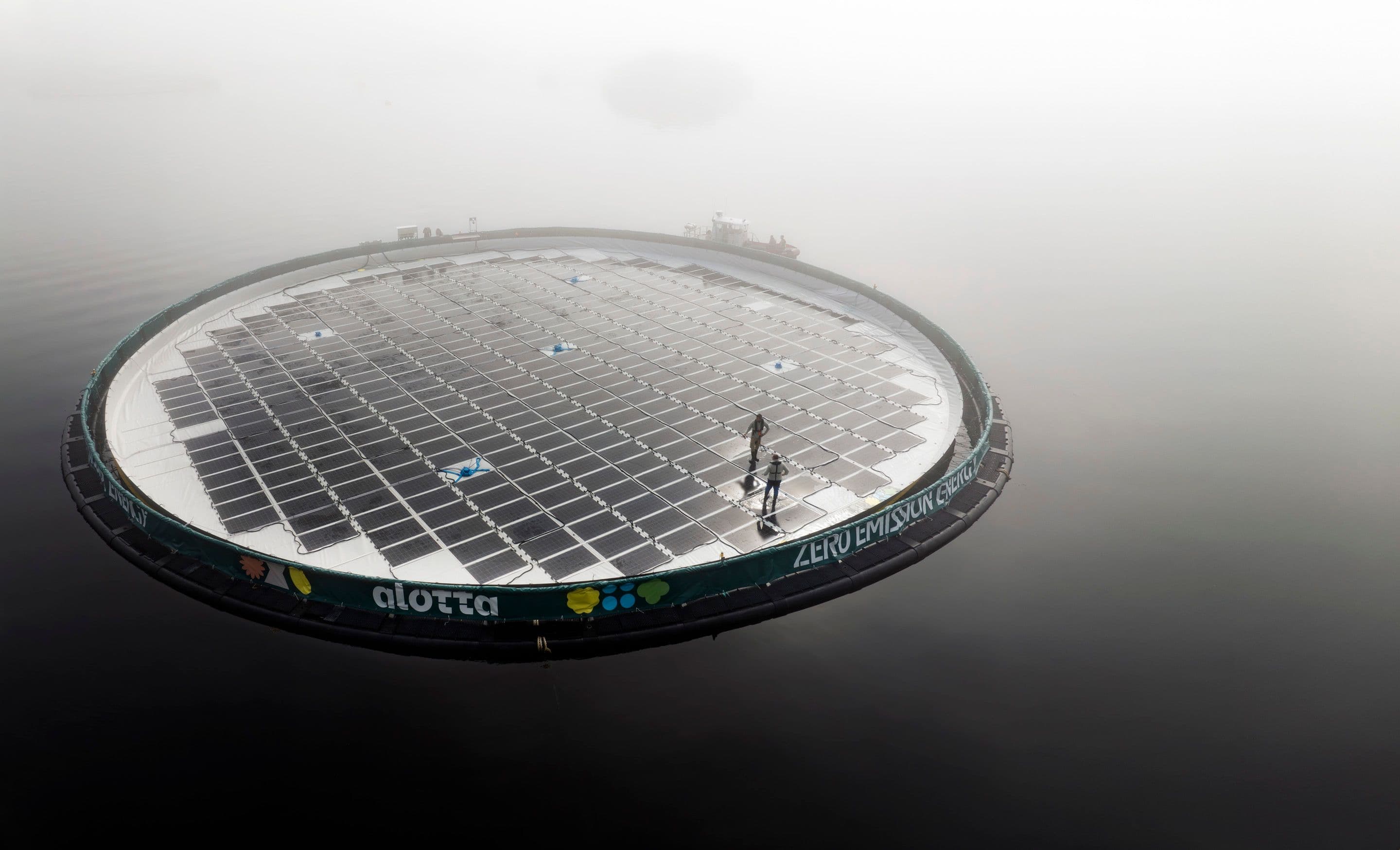 An Alotta Solar Hybrid floating in the water with two people on it